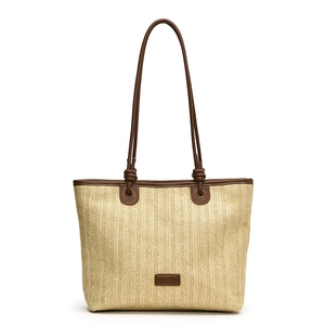 Large beige woven straw tote bag with brown leather handles for summer beach vacations