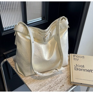 Close-up of white glossy crinkled leather tote bag with metallic buckle detail