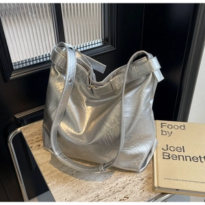 Detailed view of silver tote bag with pleated metallic texture and wide shoulder strap
