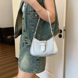 Silver crescent underarm bag in metallic leather worn by model with casual outfit