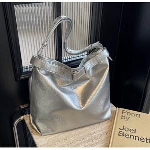 Detailed view of silver metallic tote bag with pleated texture and stylish buckle strap