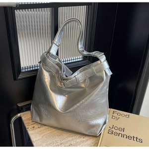 Detail of silver metallic tote bag with crinkled texture on marble surface