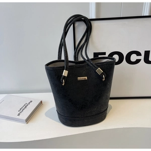 Dettaglio borsa a secchiello nera con trama vintage e placca in metallo oro