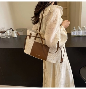 Detail of large straw tote bag with brown leather accents and fashion text design