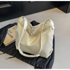Macro view of creamy white tote bag featuring pleated texture and silver metal rivets