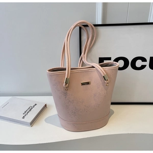 Dettaglio ravvicinato della borsa a secchiello rosa con logo oro e doppi spallacci sottili