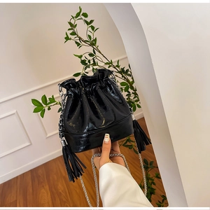 Detailed view of black bucket bag featuring crocodile texture and tassel drawstring