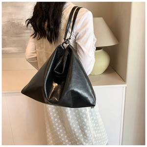 Detail of a black large capacity tote bag featuring soft oily leather and unique triangle shape
