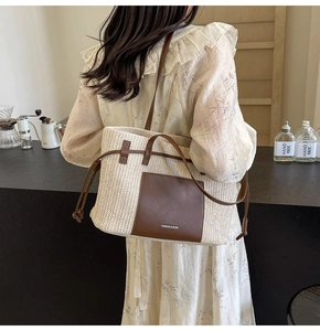 Detail of woven straw tote bag featuring brown leather pocket and adjustable drawstrings