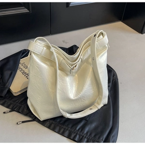 Close-up of cream hobo bag showing wrinkled leather texture and silver rivet strap
