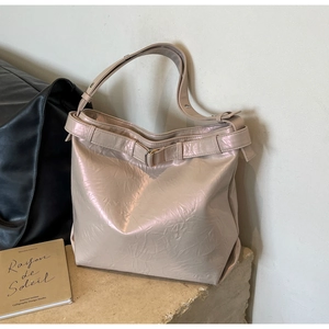 Detail of champagne oversized tote bag with pleated glossy finish and decorative belt buckle