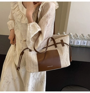 Close-up of woven straw tote bag featuring brown leather pocket and drawstring detail