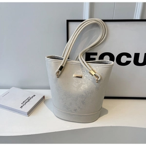 Dettaglio della borsa a secchiello bianco perla con hardware dorato e texture lucida