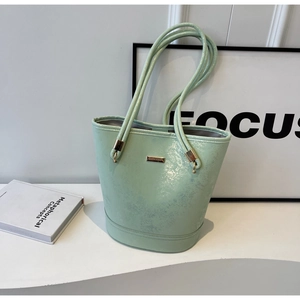 Dettaglio della borsa tote verde menta in vernice con texture cracklé e logo dorato