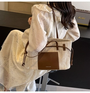 Detailed back view of a straw woven tote bag with brown leather straps for beach holidays