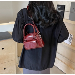Dunkelrote glänzende Mini-Handtasche und Umhängetasche getragen zu schwarzem Outfit