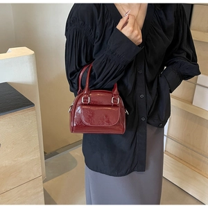 Detailansicht der weinroten Lackledertasche mit silberner Metallschnalle und Griff