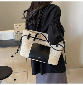 Detail of woven straw tote bag with black leather straps and fashion label decoration