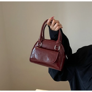 Detailansicht der weinroten Lackledertasche mit Schnallen und Tragegriff