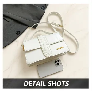 Close-up of white croc-embossed handbag showing top handle, strap, and golden logo