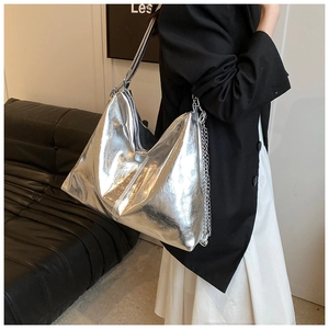 Detail showing the metallic silver crinkled texture and sleek metal chain of the tote bag