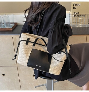 Detail of a large straw tote bag with black leather trim and drawstring for beach travel