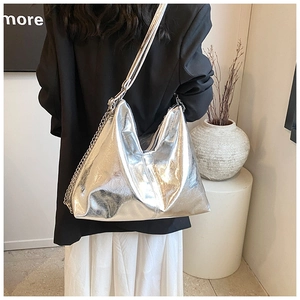 Detail of silver metallic hobo bag with a stylish chain strap on a minimalist setup