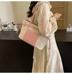 Detail of hand-woven straw tote bag with pink leather trim and side drawstring