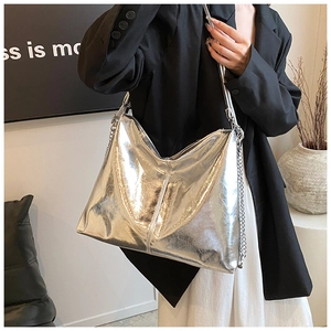 Detail of silver metallic hobo bag featuring chain strap on model in modern setting