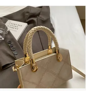 Detail of beige handbag with woven handle, golden teardrop buckle and textured leather