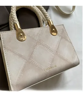 Detail of cream square bag showing woven handle, gold hardware, and lattice texture