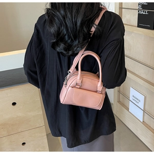 Detailansicht einer rosa Umhängetasche mit Metallreißverschlüssen und Schultergurt