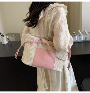 Detail of woven straw tote bag with pink leather trim and decorative side drawstrings