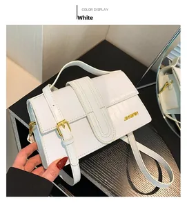 Detail of white crocodile pattern texture with golden JINGPIN metal logo on handbag