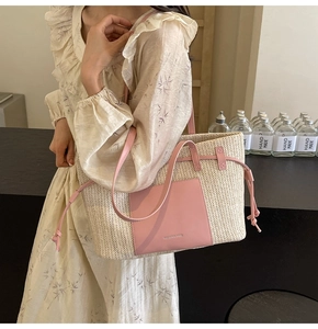 Detailed view of beige straw tote bag with pink leather pocket and drawstring tassels