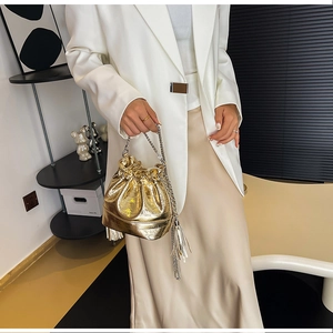Borsa a secchiello metallizzata dorata con frange e tracolla a catena e outfit moda