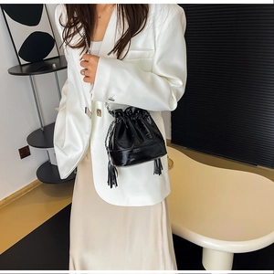 Dettaglio borsa a secchiello in vernice nera con catena argento e nappine frangiate