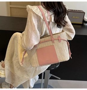 Close-up of woven straw tote bag with pink leather trim worn by a model in a cafe