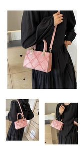 Detail of pink quilted handbag with woven handles and crossbody strap on black dress