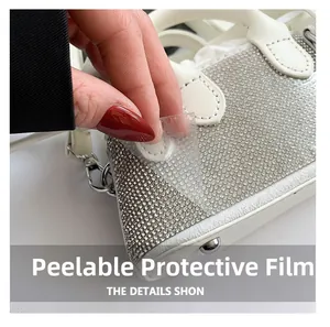 Macro detail of peeling protective film on a white rhinestone-encrusted luxury handbag