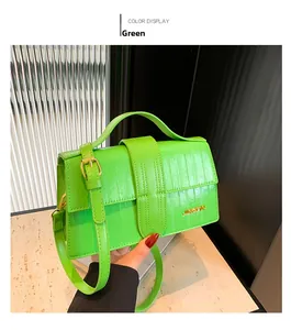 Close-up of bright green crocodile texture handbag with gold metal logo and long strap