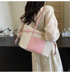 Detail of woven straw tote bag featuring pink leather pocket and drawstring tassels