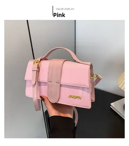 Pink faux leather handbag with crocodile pattern held against a cozy home background