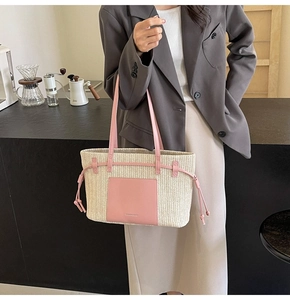 Detail of woven straw tote bag with pink leather pocket and drawstring on shoulder strap