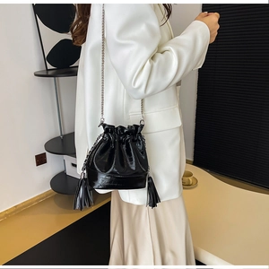 Détail du sac seau en cuir verni noir avec glands à franges et fine chaîne argentée