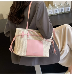 Detail of woven straw tote bag with pink leather pocket worn over the shoulder