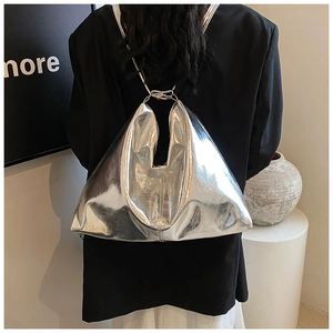 Detail of silver metallic triangle bag with chain strap against a black suit