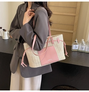 Detail of woven straw tote bag with pink leather pocket and shoulder straps on a model