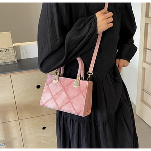 Detailed close-up of a pink quilted crossbody bag with a woven handle and gold hardware