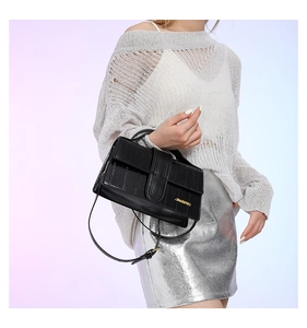 Detail of crocodile embossed texture on a black crossbody bag with golden hardware